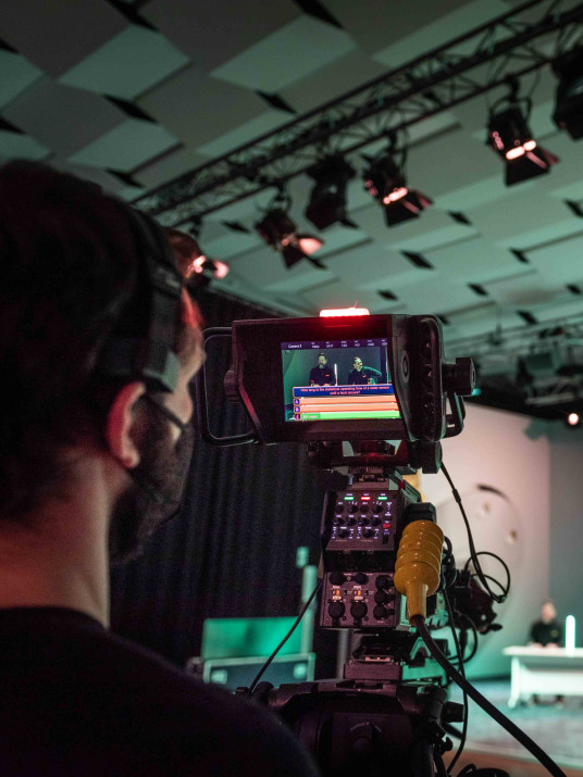 Ein Kameramann überträgt ein Event live am Kamerazug. Veranstaltungspräsentation, Livestream, Ablaufregie Event, Teleprompter Bühne