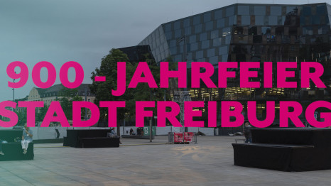 Openair-Eventlocation, im Hintergrund die Unibibliothek Freiburg mit eingeblendetem Eventtitel. Team Beinert, Gebäudemapping, Projektion, live übetragen, Livestream, Pan.Optikum